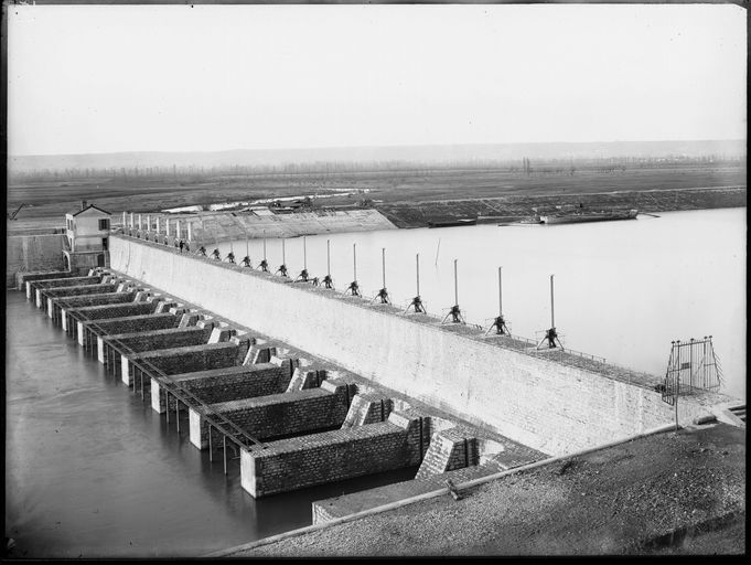 Montrer la barrage de Jonage en construction dans le cadre du chantier du canal de Jonage et de l'usine hydroélectrique de Cusset